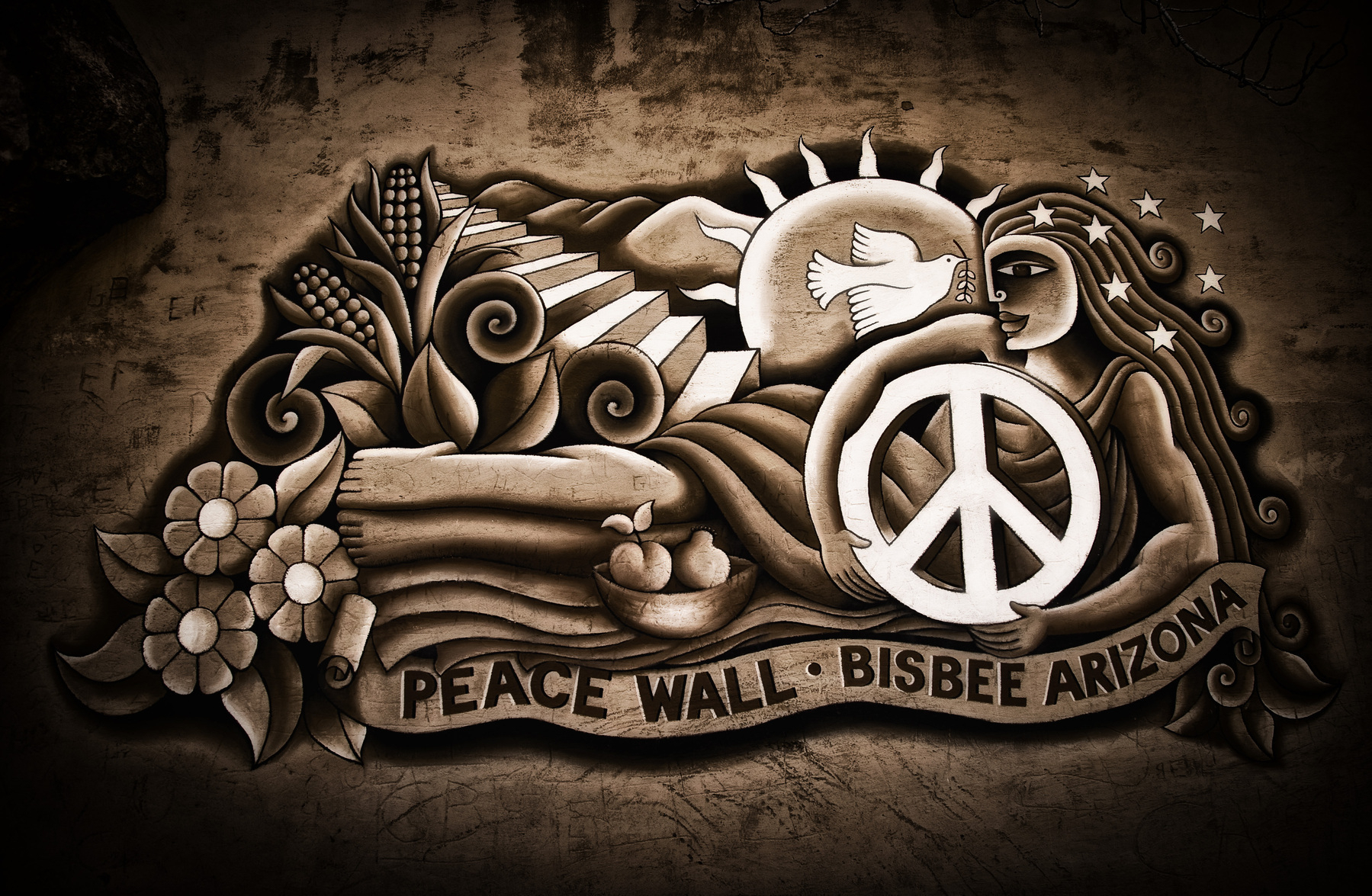 Auto-generated description: A mural featuring a stylized peace symbol, a dove, and various decorative elements with the inscription Peace Wall 