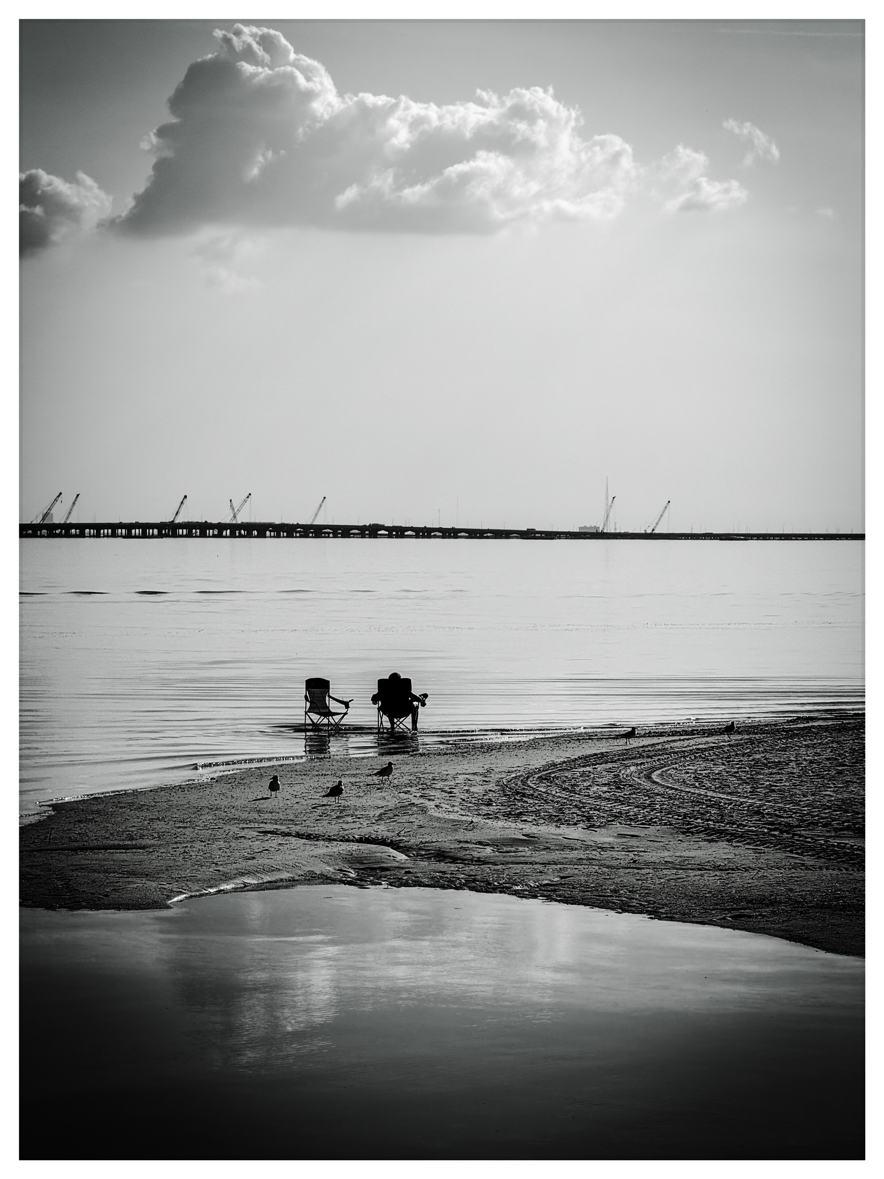 two people sitting in chairs in the shallow waters of a florida bay.