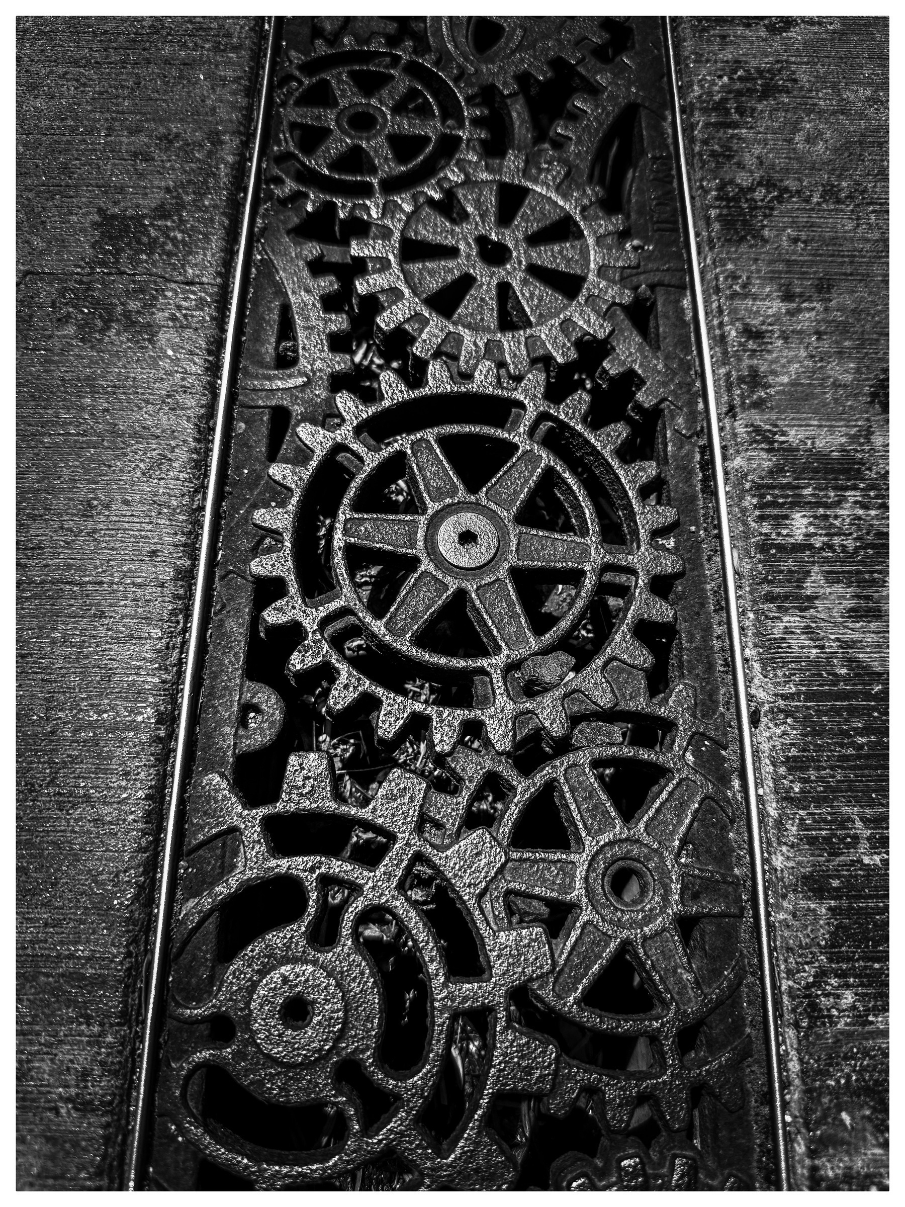 Auto-generated description: A collection of interlocking gears is intricately arranged in a narrow, rectangular frame.