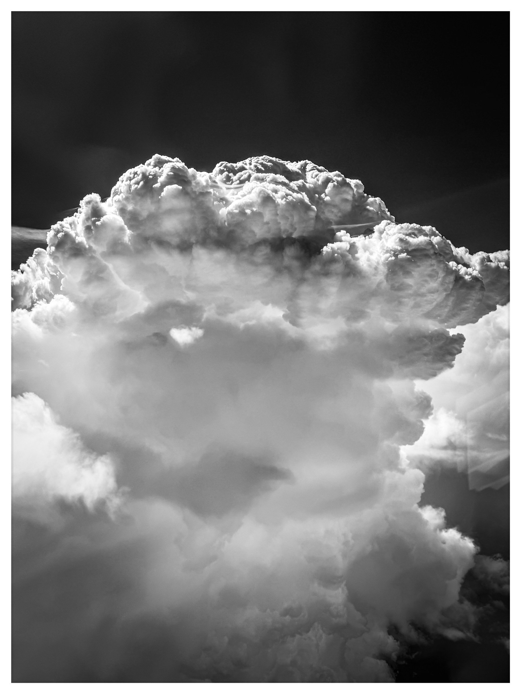 Auto-generated description: A large, dramatic cloud formation dominates the sky in striking black and white.