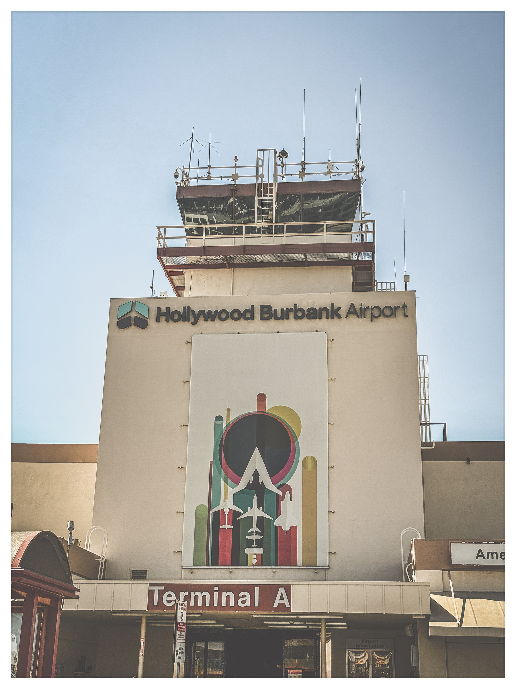 Auto-generated description: Hollywood Burbank Airport's Terminal A is depicted with a colorful abstract art piece on the building facade.