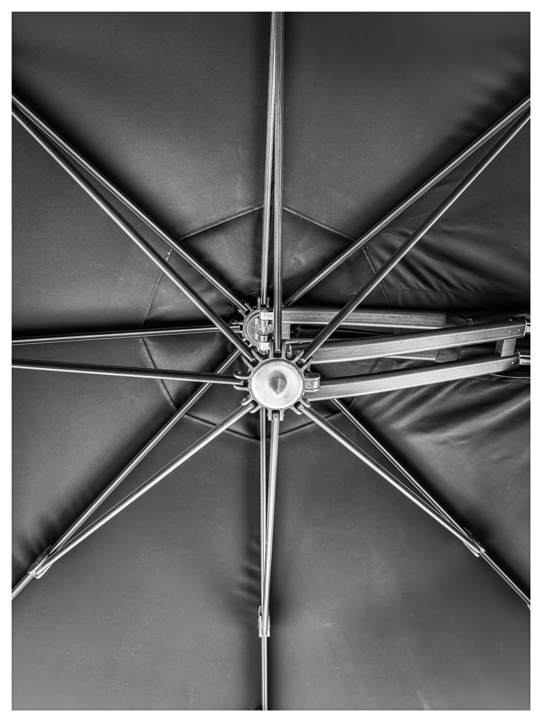 Auto-generated description: A black and white close-up view of the underside of an open umbrella, showcasing the central hub and radiating spokes.
