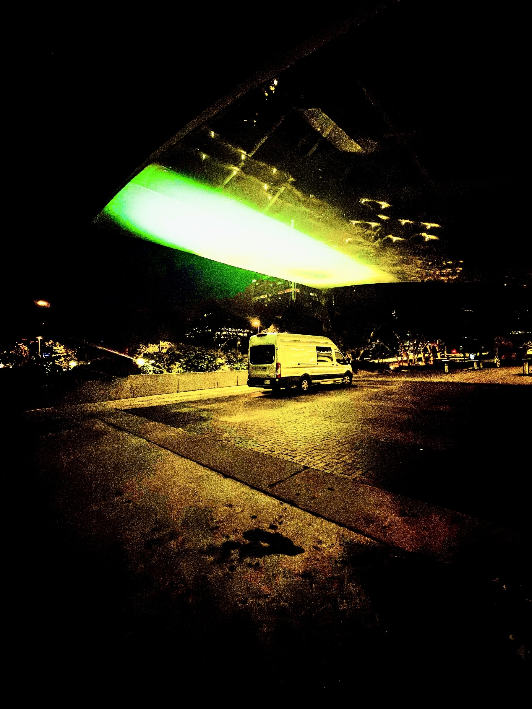 Auto-generated description: A van is parked in a dimly lit area with a striking green light illuminating a section of the scene.