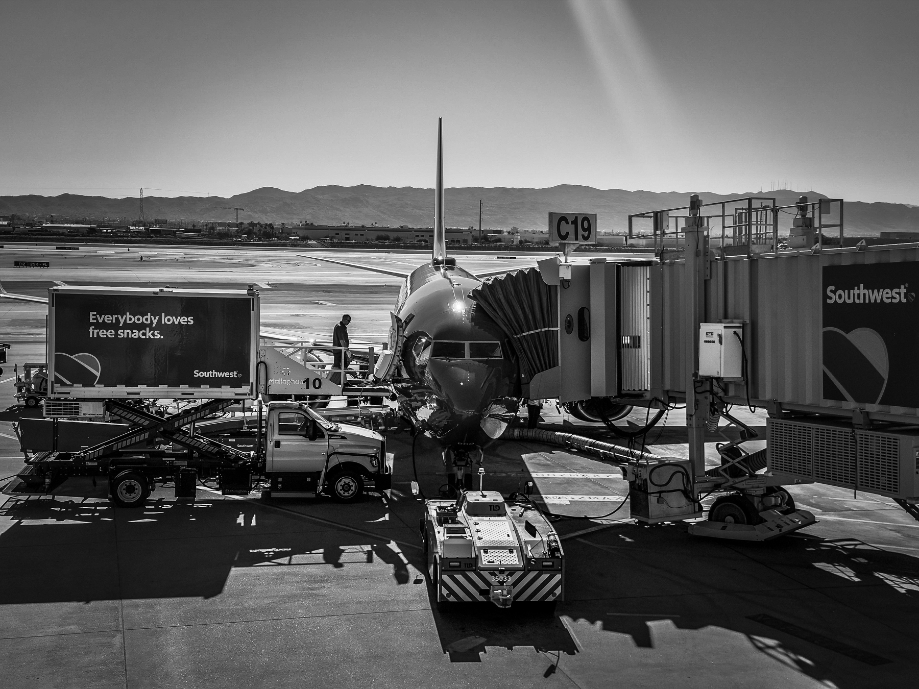 A Boeing 737 plane is parked at a gate with ground service vehicles surrounding it at an airport.