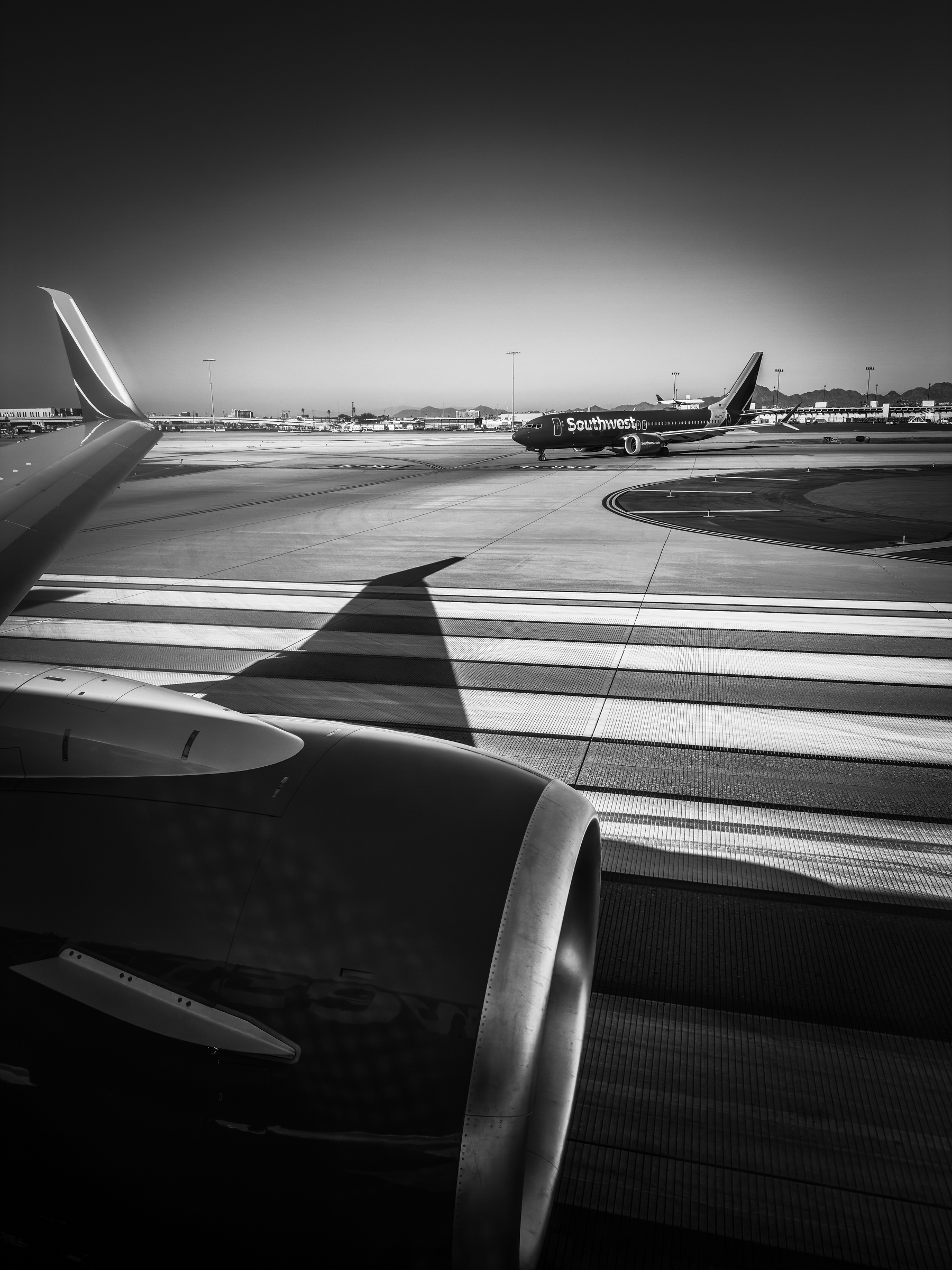 A plane is on the tarmac near another plane's engine at an airport.