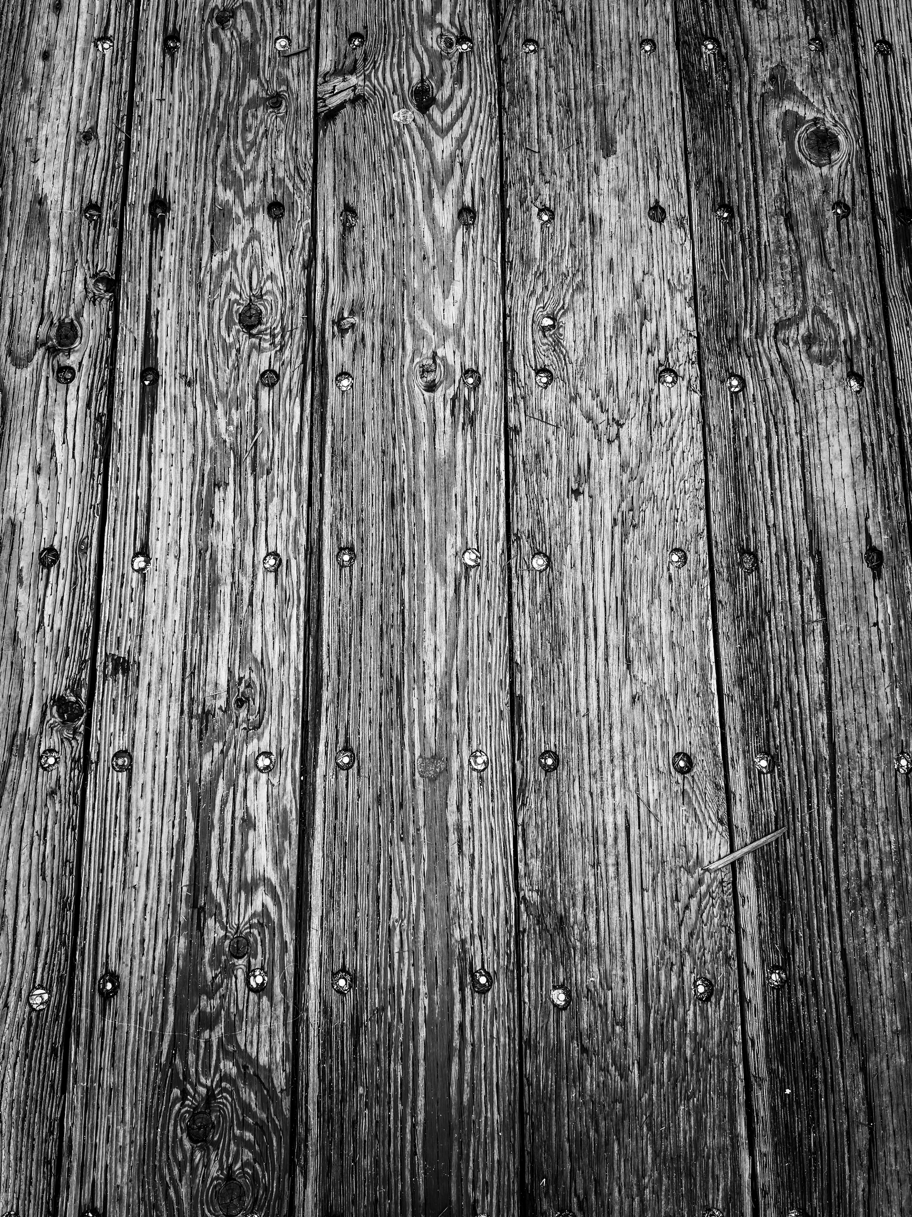 Auto-generated description: Weathered wooden planks with visible grain and scattered metal rivets create a rustic texture.