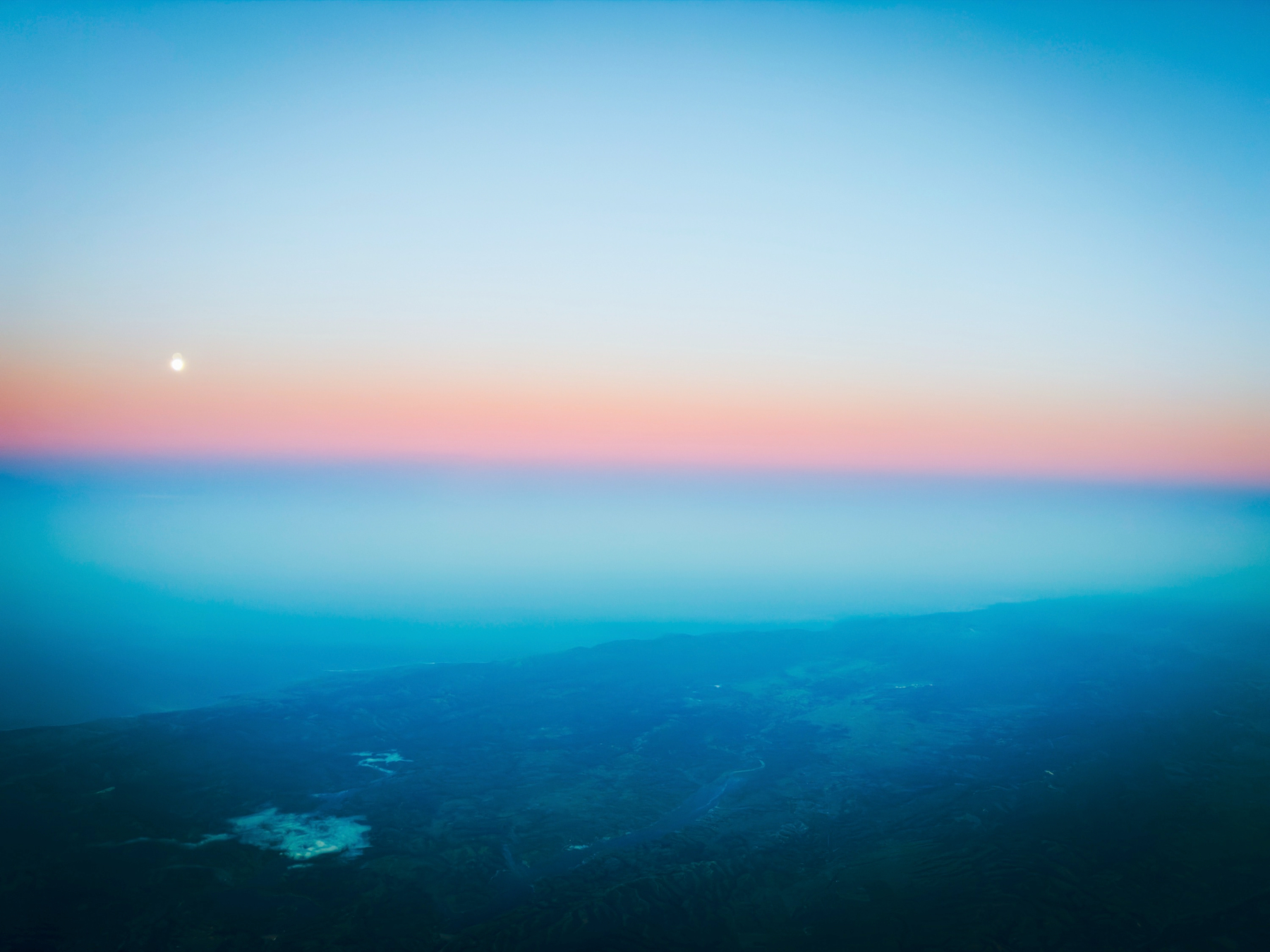 Auto-generated description: A serene and colorful sunset over a vast landscape with a distant horizon and a glowing sky.