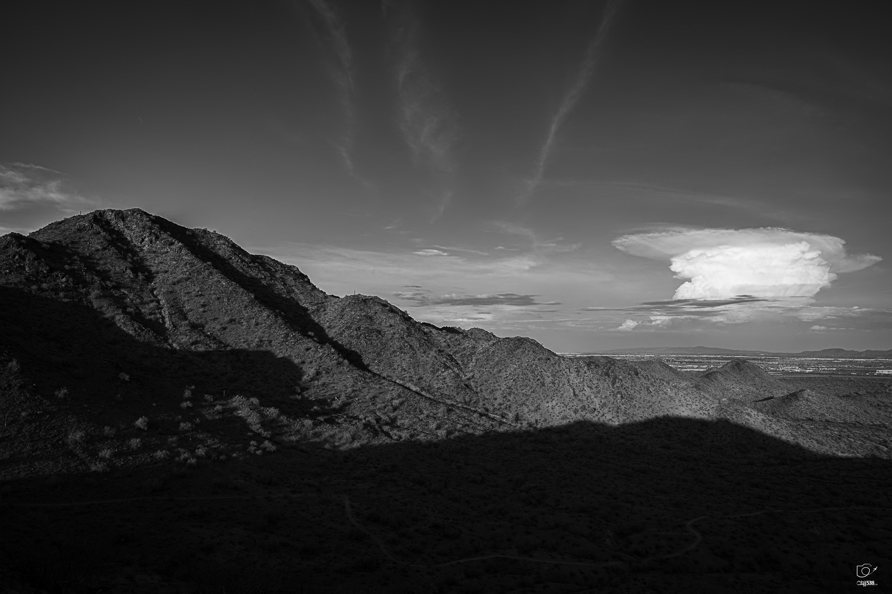 Auto-generated description: A mountainous landscape under a partly cloudy sky is captured in black and white.