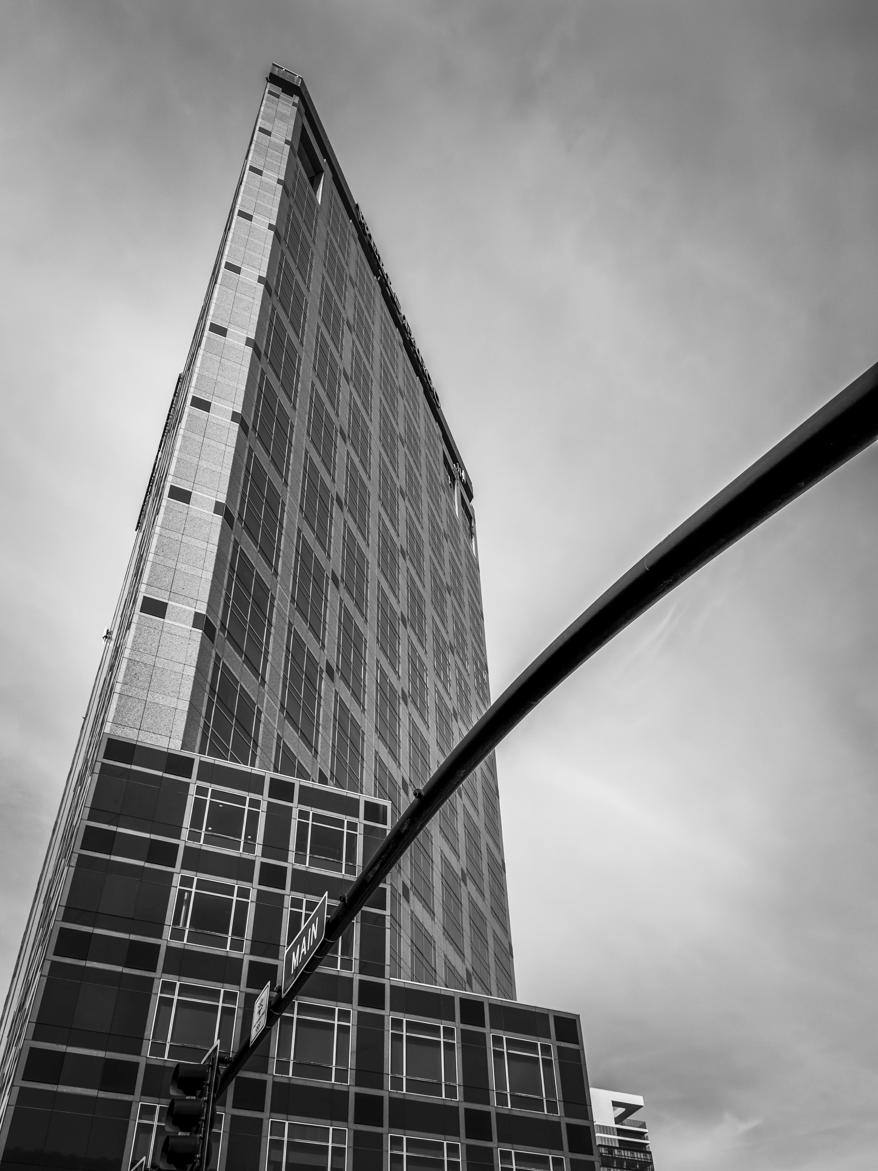 Auto-generated description: A towering skyscraper stretches into the sky, viewed from below next to a traffic light.
