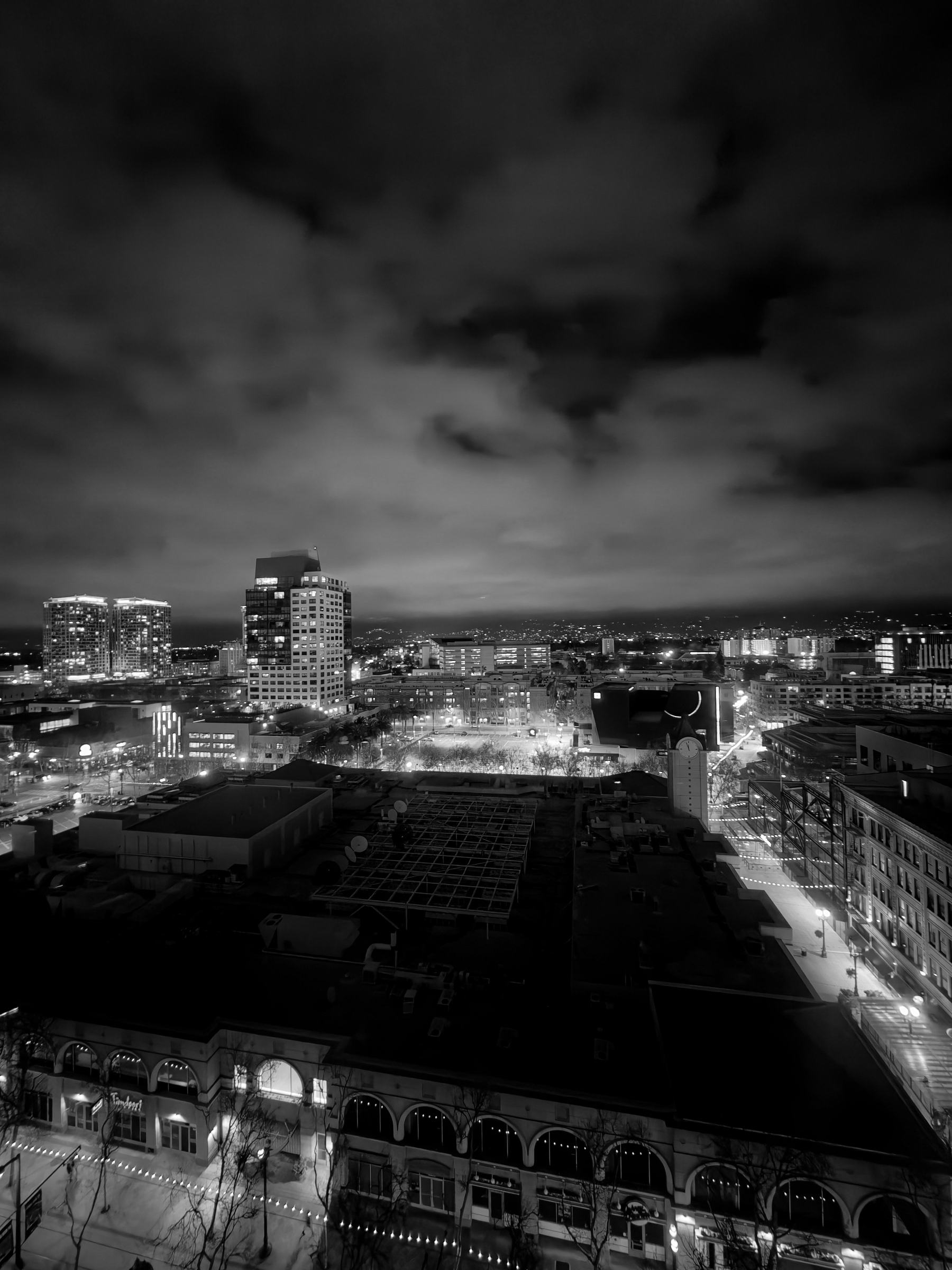 Auto-generated description: A cityscape at night is illuminated by building lights under a cloudy sky.